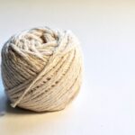 Detailed close-up of a natural cotton yarn ball on a white background, perfect for textile and crafting themes.